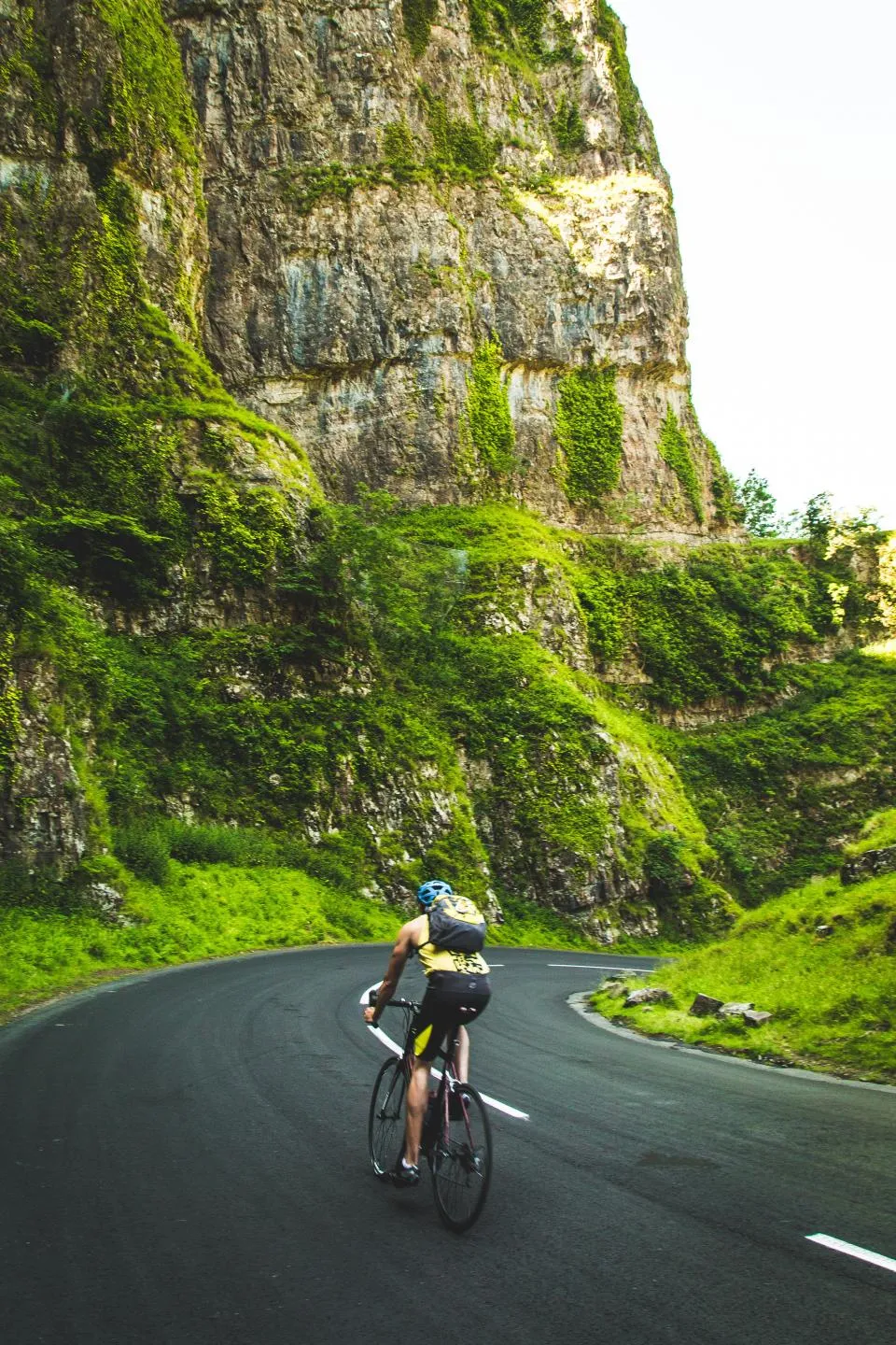 A cyclist climbing a switchback road through a gorge